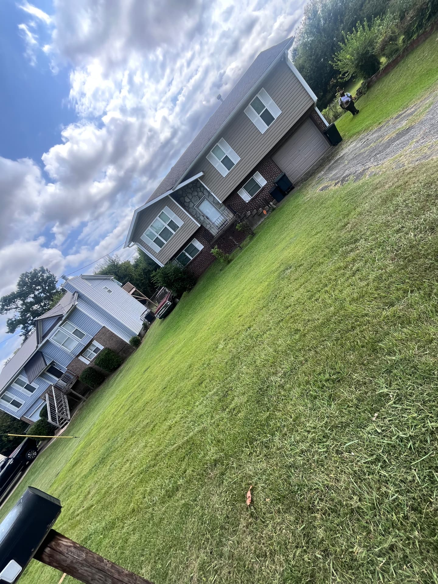 Large open lawn in front of two suburban homes with a red truck parked between them and a mailbox at the road.